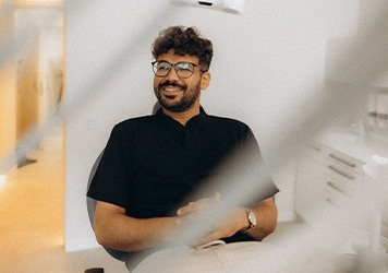 Patient with black glasses smiling in treatment chair