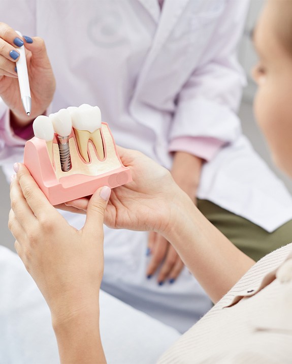 Dentist showing patient a model dental implant