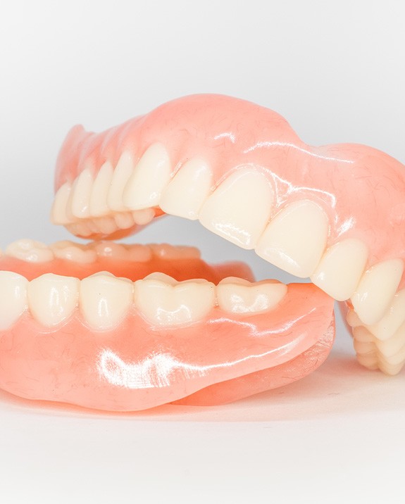 Complete set of shiny dentures on white surface