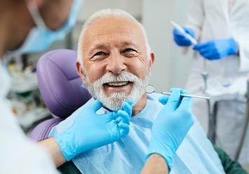 White-gloved hands holding a complete set of dentures