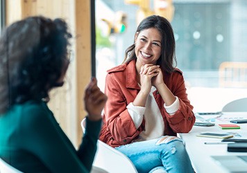 Two women smiling and chatting at meeting table