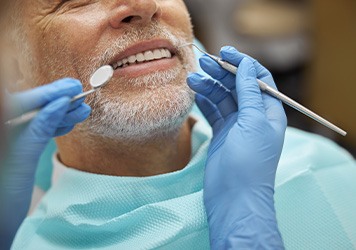 Nose-to-shoulder view of man with white beard hair about to undergo dental exam