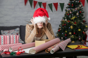 Woman in a Santa hat stressing out with an unwrapped gift